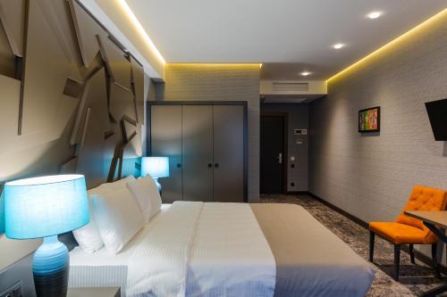 a bedroom with a white bed and a desk and a chair at Tapis Rouge Design Boutique Hotel in Batumi