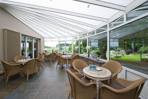 a restaurant with tables and chairs and windows at Hotel des Ardennes in Corbion