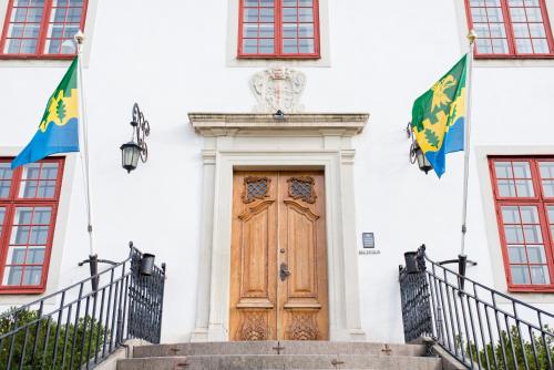 a building with a wooden door and two flags at Mauritzbergs Slott & Golf in Mauritsberg