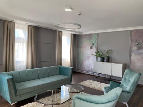 a living room with a blue couch and two chairs at Boutique Hotel Center in Kecskemét
