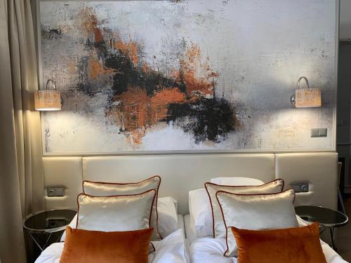 a bedroom with two beds and a painting on the wall at Boutique Hotel Center in Kecskemét