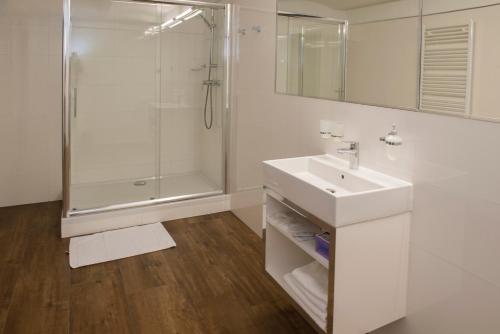 a white bathroom with a sink and a shower at Boutique Hotel Center in Kecskemét