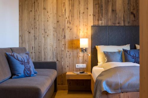 a bedroom with a bed and a couch and a lamp at Das Grünholz Aparthotel in Mühlbach am Hochkönig