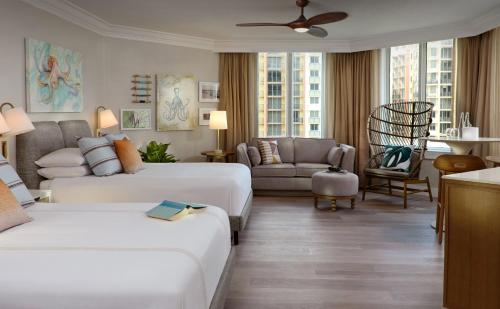 a hotel room with two beds and a couch at Pelican Grand Beach Resort, a Noble House Resort in Fort Lauderdale