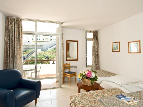 sala de estar con cama, sofá y ventana en Apartamentos Edificio Albufeira - Alojamento Local, en Albufeira