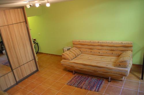 un sofá sentado en una sala de estar junto a una puerta en Kalnas apartaments, en Juodkrantė