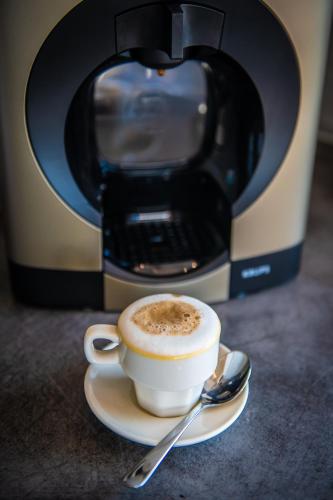 a cup of coffee on a plate next to a coffee maker at Artist Terrace Apartments in Mellieħa
