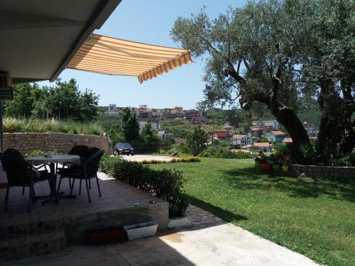 a patio with a table and chairs in a yard at Zelena Maslina in Bar