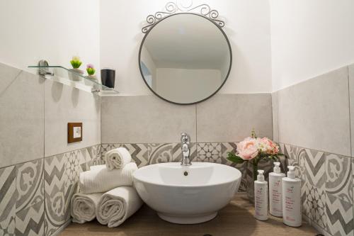 W łazience znajduje się umywalka i lustro. w obiekcie Casa Rosa al Molo by Wonderful Italy w Genui