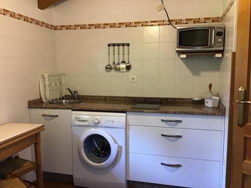 eine Küche mit einer Waschmaschine und einer Mikrowelle in der Unterkunft Camangu-Estudio in Ribadesella