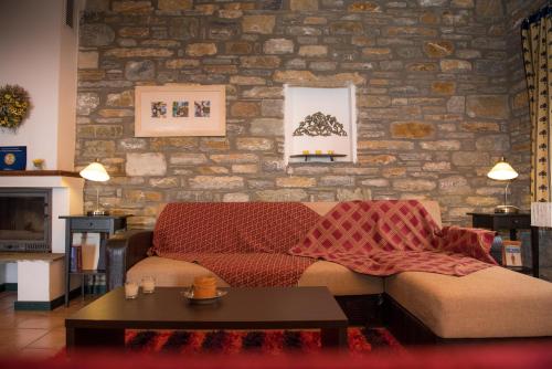 a living room with a couch and a brick wall at Pelion Goddess Villas in Agios Georgios Nilias