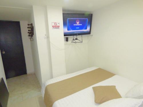 a room with a bed and a tv on a wall at SUITE SANTA LUCIA HOTEL BOUTIQUE in Sogamoso