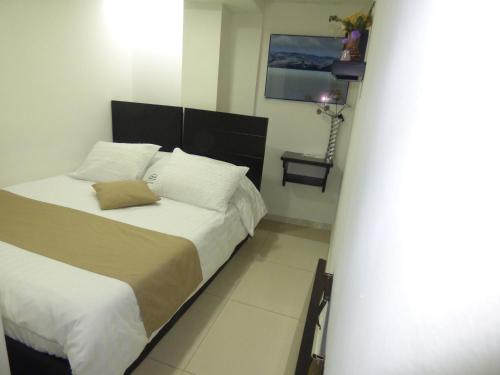a bedroom with a bed with white sheets and pillows at SUITE SANTA LUCIA HOTEL BOUTIQUE in Sogamoso