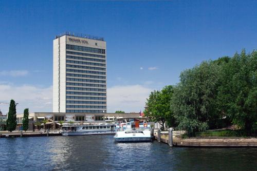 two boats docked in a river with a tall building at Mercure Hotel Potsdam City in Potsdam