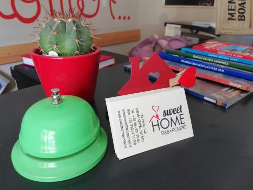 a green hat and a sign on a table with a cactus at B&B Sweet Home Two Steps From The Ruins... in Pompei