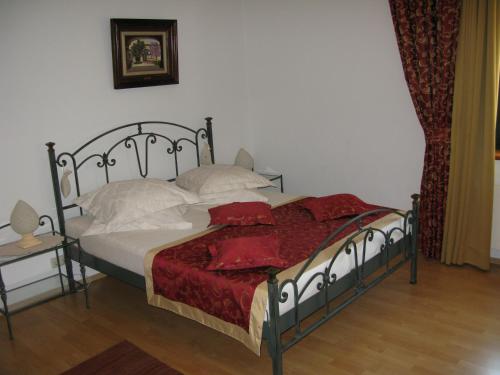 a bedroom with a bed with red sheets and pillows at Bed and Breakfast Villa Iris in Mošćenička Draga