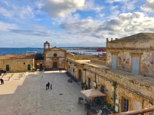 an old building with a clock tower next to the ocean at BeB L'ALLORO in Pachino