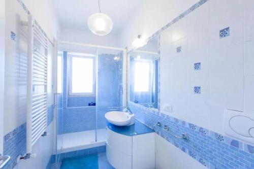 y baño azul y blanco con lavabo y ducha. en Terraced Park View Penthouse, en Roma