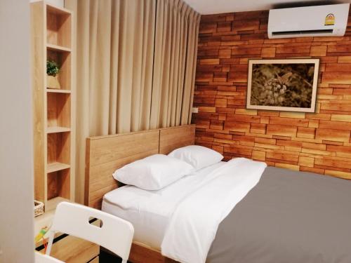 a bedroom with a white bed with a brick wall at White House Hostel in Bangkok