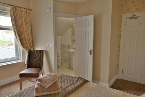 a bedroom with a bed and a chair and a window at Cul-Erg House & Kitchen in Portstewart
