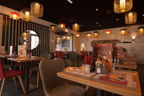a restaurant with tables and chairs and chandeliers at ibis Marseille Provence Aéroport in Marignane