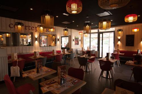 a restaurant with tables and chairs and chandeliers at ibis Marseille Provence Aéroport in Marignane