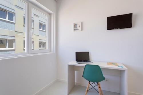 einen Schreibtisch mit Laptop neben einem Fenster in der Unterkunft Next Inn in Portimão