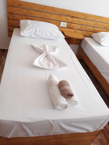 a white bed with towels and a bow on it at Beleris Rooms in Himare