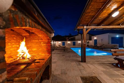 a brick fireplace next to a swimming pool at night at Vitez's House Novigrad/Knight's House Novigrad in Novigrad Dalmatia