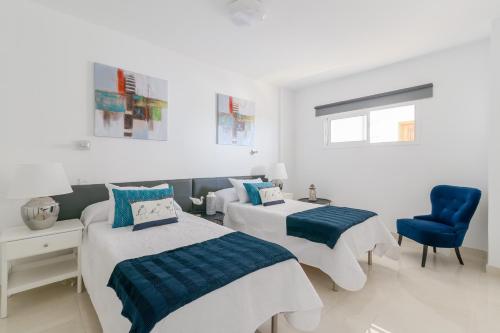 a bedroom with two beds and a blue chair at Tropical Treat in Playa del Ingles