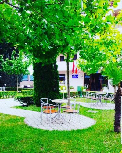 a table and chairs under a tree in a park at Hotel Ambasador Garden in Lezhë