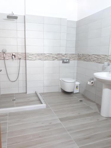 uma casa de banho com um chuveiro, um WC e um lavatório. em Beleris Rooms em Himare