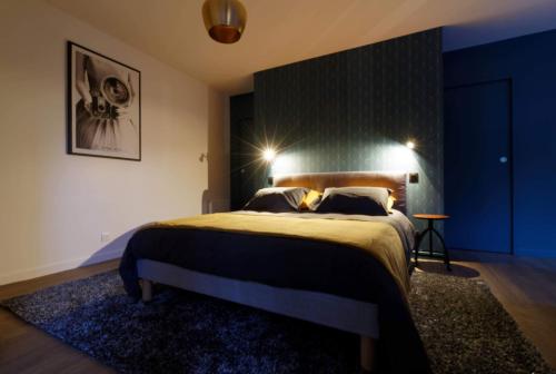 a bedroom with a large bed with a blue wall at La Douce Escapade in Sizun