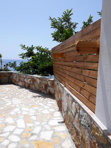 a stone retaining wall with a wooden fence at Beleris Rooms in Himare