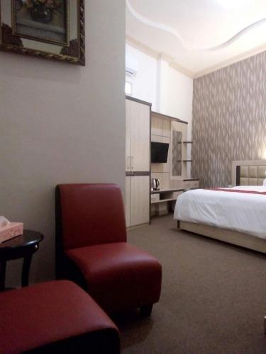 a hotel room with a bed and a red chair at Hotel Assyifa Tanjungbalai in Tanjungbalai
