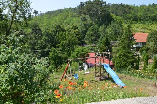 a playground with a slide in a garden at Ezüsthíd Apartman in Balatongyörök