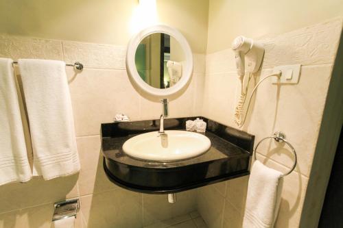 a bathroom with a sink with a mirror and a phone at Hotel Plaza Apolo in Sao Paulo