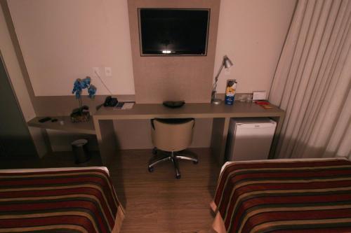 a room with a desk with a computer and a bed at Hotel Beaga Convention Expominas by MHB in Belo Horizonte