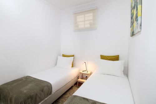 2 Betten in einem Zimmer mit weißen Wänden in der Unterkunft Sete Rios, Near Zoo Lisboa/ free Wifi in Lissabon