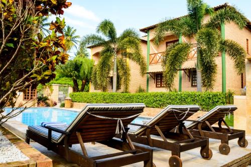 two lounge chairs and a pool in front of a house at Hotel Vento Brasil in Paracuru