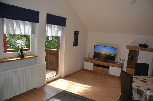 a living room with a flat screen tv and two windows at Ferienwohnung Wildgatter in Grafenwiesen