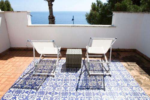 two chairs and a table on a patio with the ocean at Villa Mallandrino in Mondello