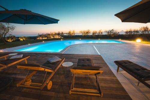 a swimming pool with chairs and a table and an umbrella at Wine Residence Cattunar in Brtonigla