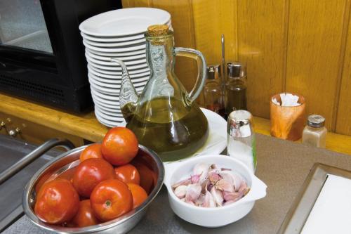 Una encimera de cocina con un bol de tomates y una botella. en Hotel Avenida, en La Seu d'Urgell