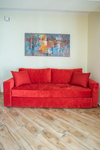 a red couch in a room with a wooden floor at Kavadias Apartments in Vasiliki