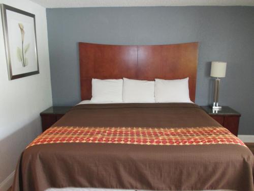 a bedroom with a large bed with a brown headboard at Travel Inn and Suites in Lakehurst