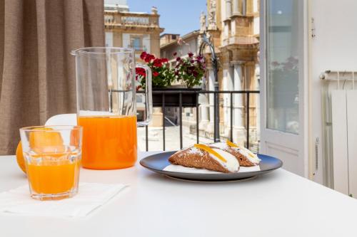 una mesa con un plato de comida y un vaso de zumo de naranja en I Balconi di San Domenico en Palermo