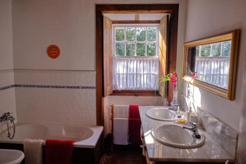 baño con 2 lavabos, bañera y ventana en A Charming , Traditional Cottage at Quinta da Ribeira en Vila Nova de Poiares