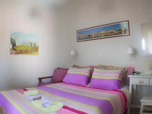 a bedroom with a bed with purple and pink sheets at Kalokenti Studios in Aegina Town