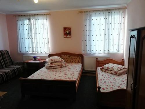 a bedroom with two beds and a couch and windows at Hostel „La Galan” in Rădăuţi
